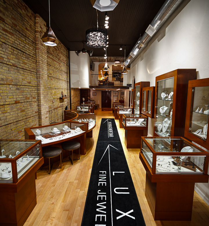 Elegant jewelry showroom with wooden display cases, an exposed brick wall, and a long black runner rug.